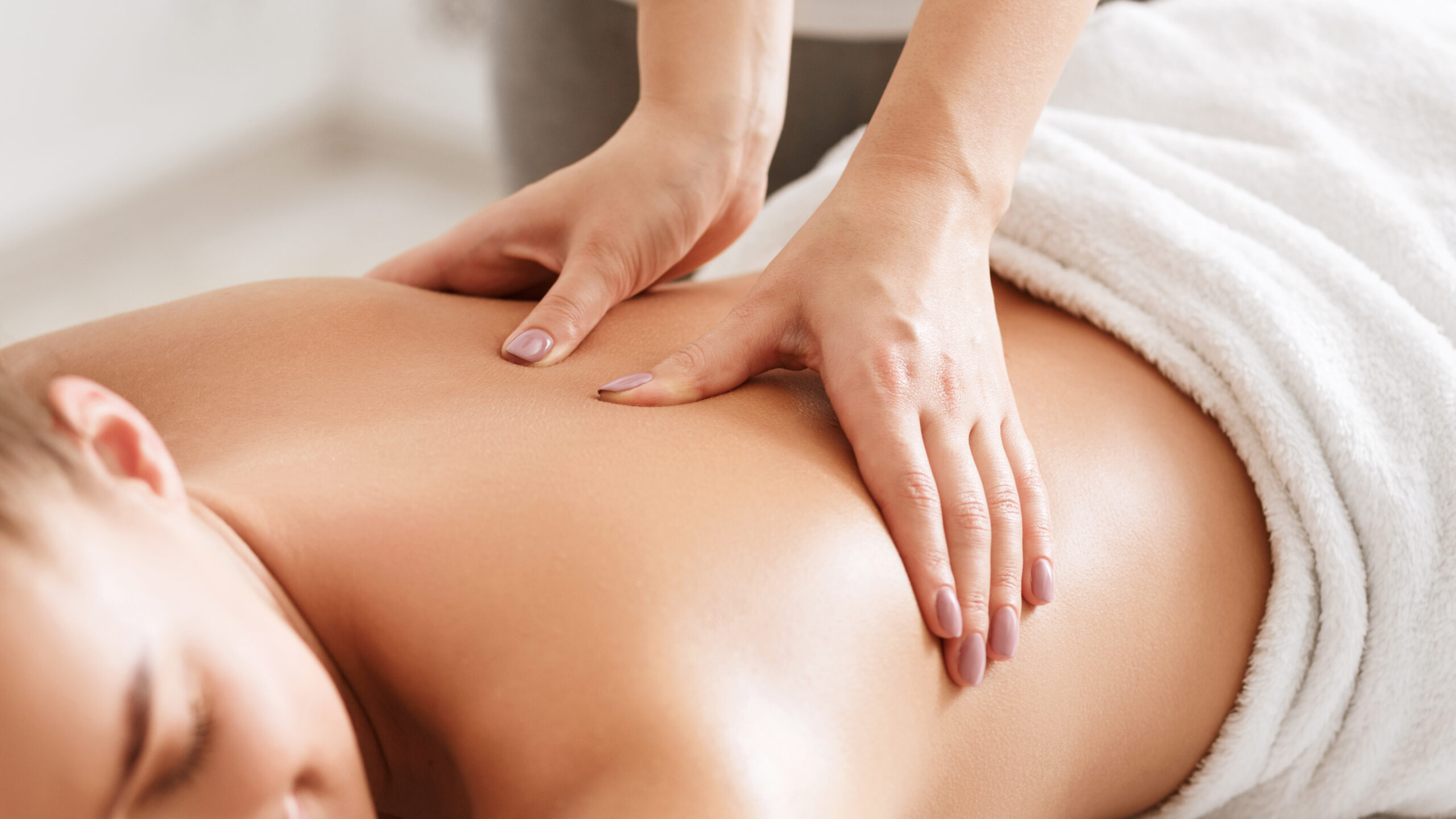 Body care. Young girl having massage, relaxing in spa salon, closeup