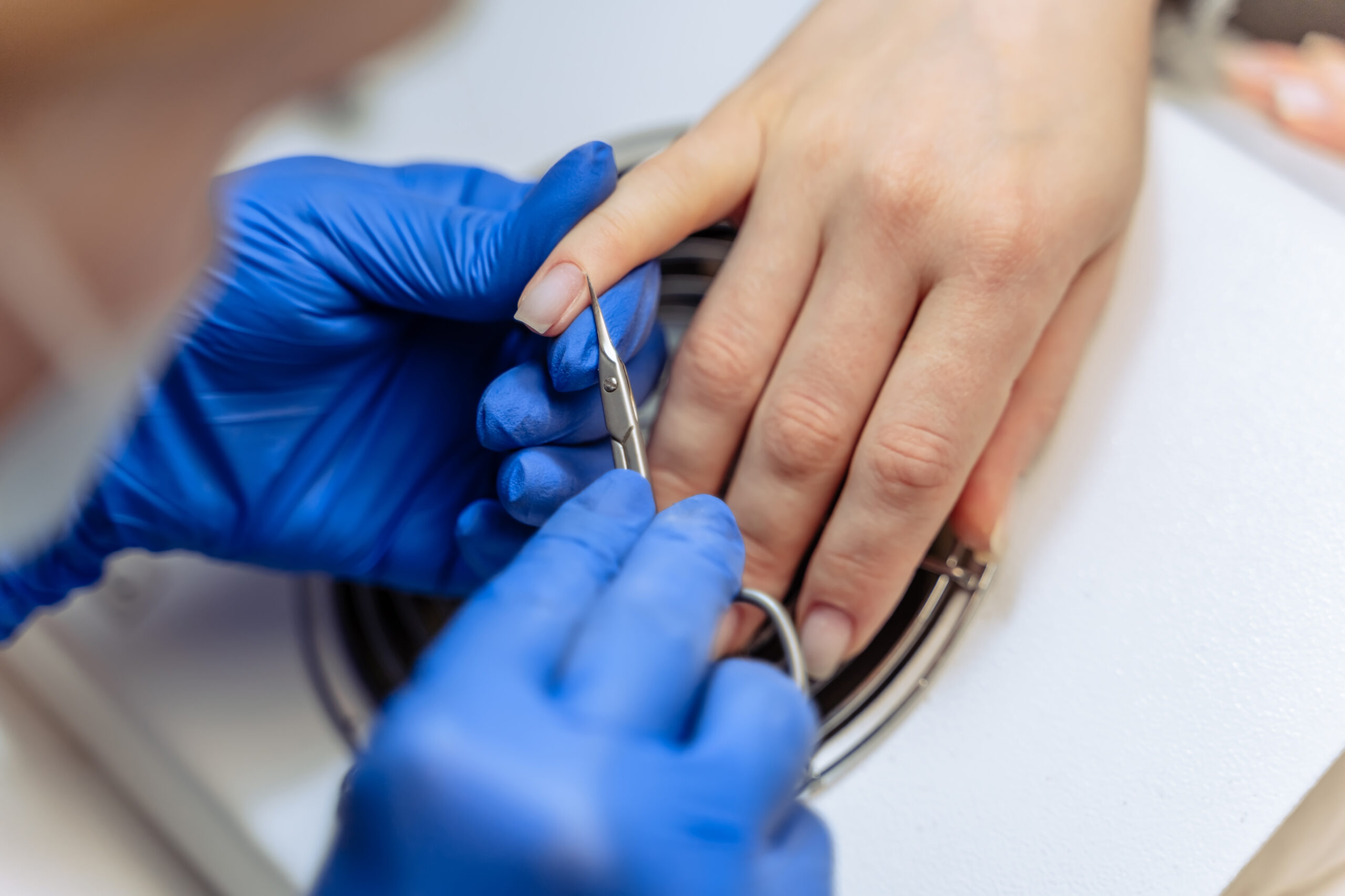 Closeup process of professional manicure at beauty salon. Professional manicurist removes dry cuticle skin near nails cutting it with scissors. Real time full hd footage.